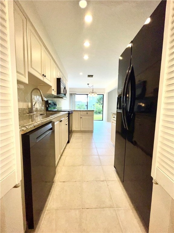 kitchen with hanging light fixtures, black appliances, light tile patterned floors, sink, and light stone countertops