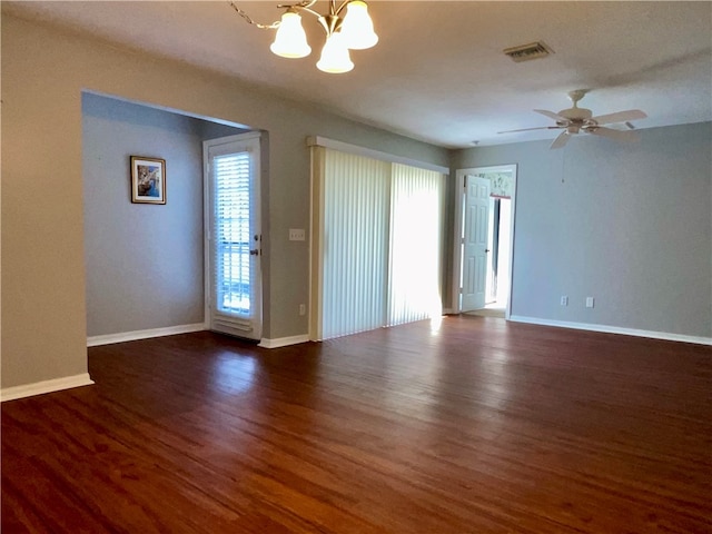 empty room featuring dark hardwood / wood-style flooring and ceiling fan with notable chandelier