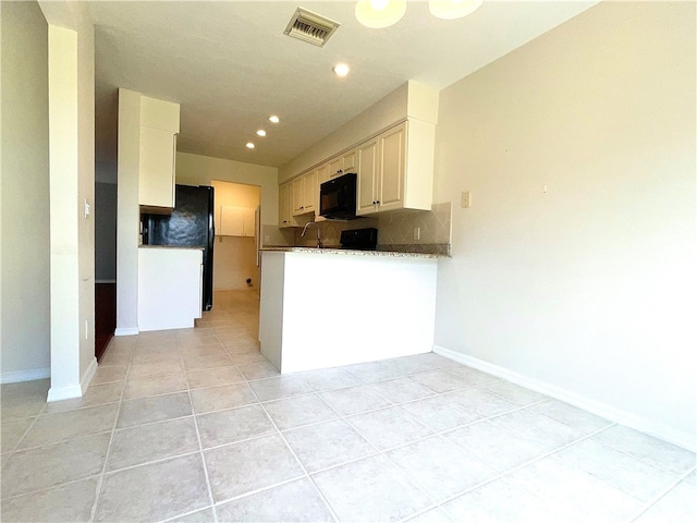 kitchen with kitchen peninsula, light tile patterned floors, stone counters, white cabinets, and decorative backsplash