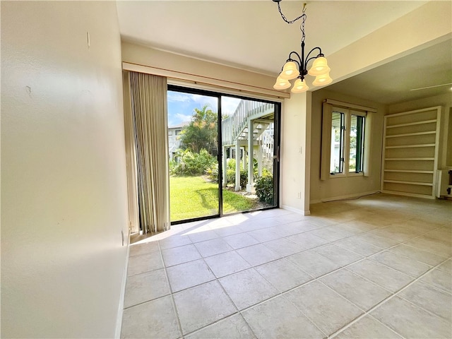 spare room featuring plenty of natural light, a notable chandelier, and light tile patterned flooring