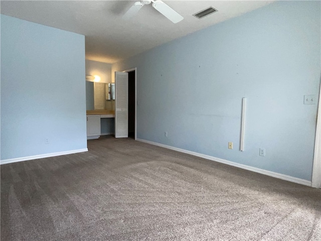 unfurnished room with dark colored carpet and ceiling fan