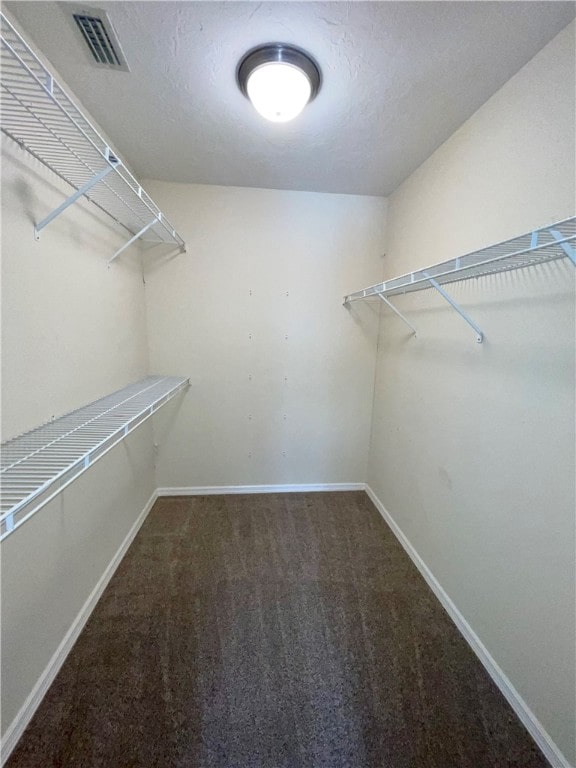 walk in closet featuring dark carpet