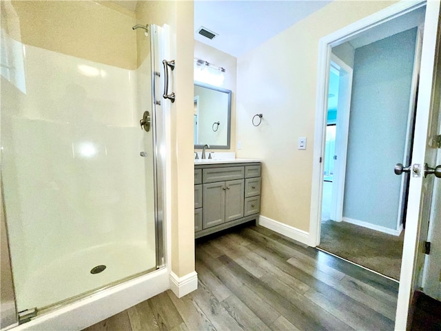 bathroom featuring hardwood / wood-style floors, vanity, and a shower with door