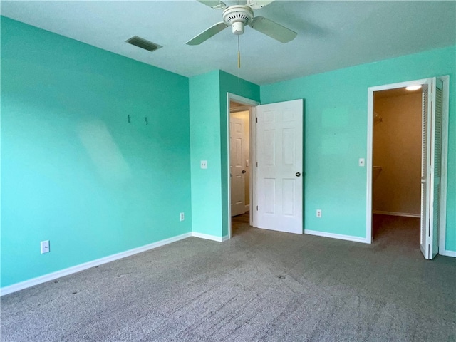 unfurnished bedroom featuring carpet, ceiling fan, and a walk in closet