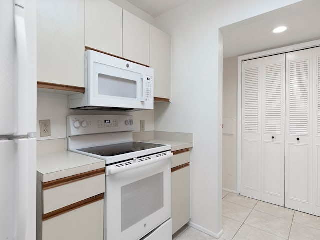 kitchen featuring light tile patterned floors, white appliances, and white cabinetry