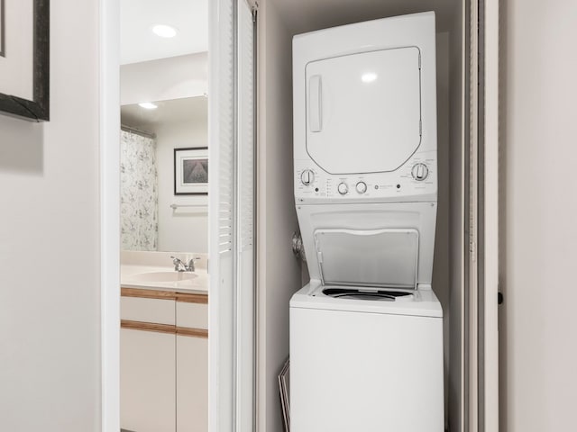 clothes washing area featuring stacked washer / dryer and sink