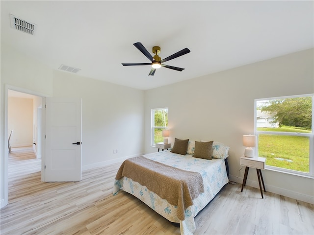 bedroom featuring ceiling fan, multiple windows, and light hardwood / wood-style flooring