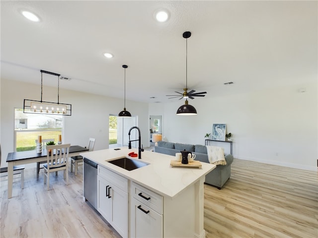 kitchen with dishwasher, a kitchen island with sink, sink, ceiling fan, and white cabinetry