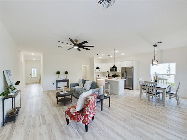 living room with ceiling fan, light hardwood / wood-style flooring, and sink