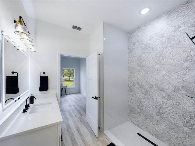 bathroom featuring a tile shower, vanity, and hardwood / wood-style flooring