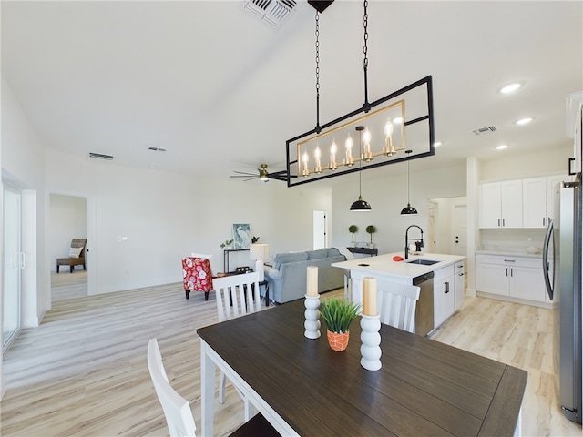 dining area with ceiling fan, light wood-type flooring, and sink