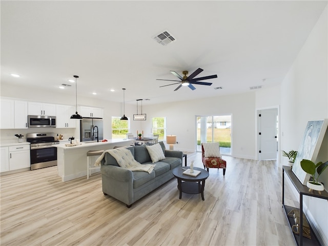 living room with ceiling fan, light hardwood / wood-style flooring, and sink