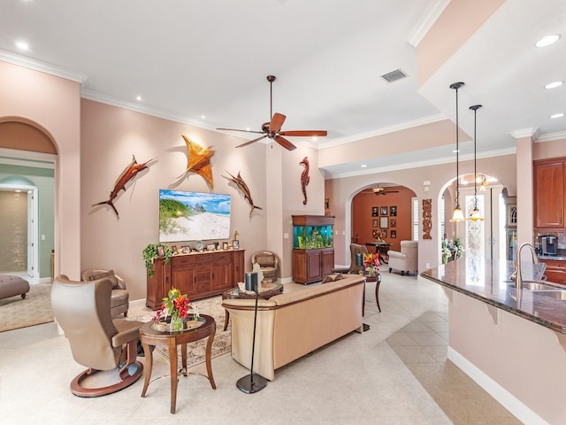 living room featuring ceiling fan, ornamental molding, and sink