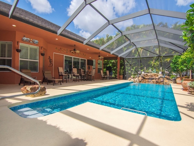 view of pool with pool water feature, ceiling fan, a patio, and glass enclosure