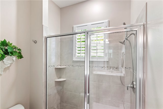 bathroom featuring toilet and a shower with shower door