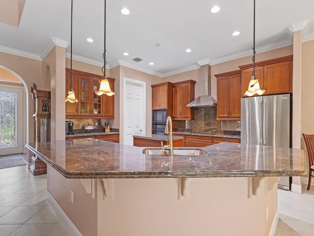 kitchen with black appliances, a breakfast bar, wall chimney range hood, and sink