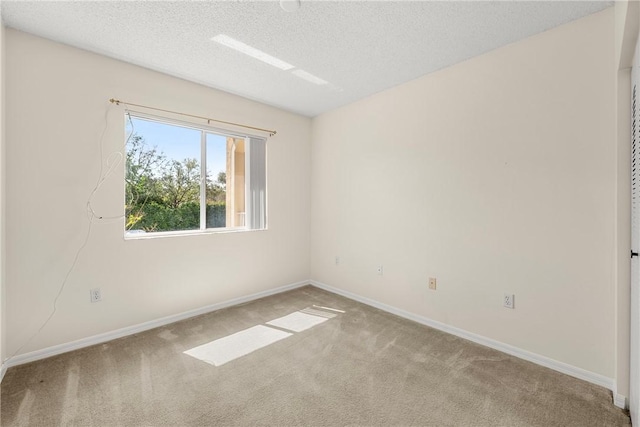 carpeted empty room with a textured ceiling and baseboards