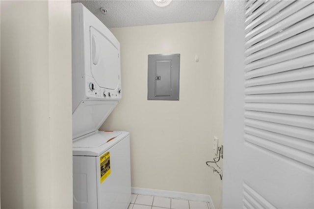 laundry area featuring stacked washer and clothes dryer, a textured ceiling, laundry area, electric panel, and baseboards