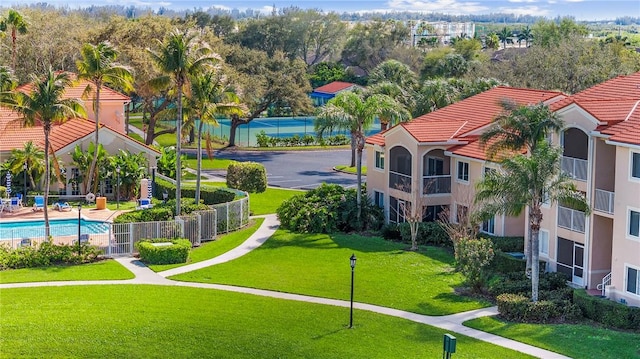 view of community with a pool, a lawn, and fence