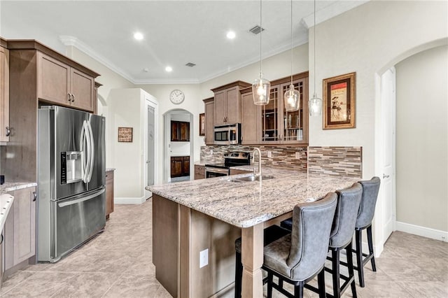 777 Fortunella Cir SW, Vero Beach, FL 32968 - kitchen with light stone countertops, arched walkways, a sink, appliances with stainless steel finishes, and a kitchen bar
