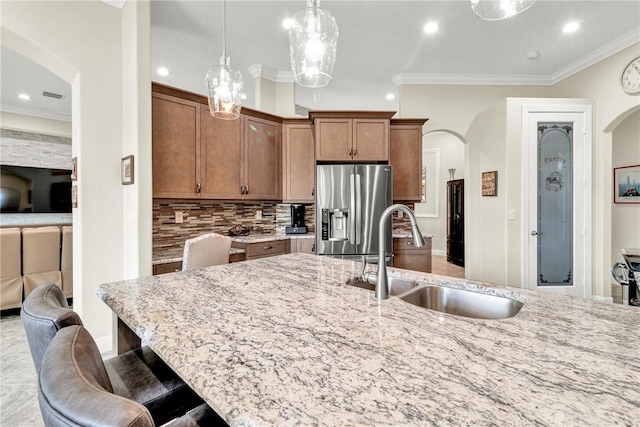 777 Fortunella Cir SW, Vero Beach, FL 32968 - kitchen with arched walkways, stainless steel fridge, light stone counters, and a sink