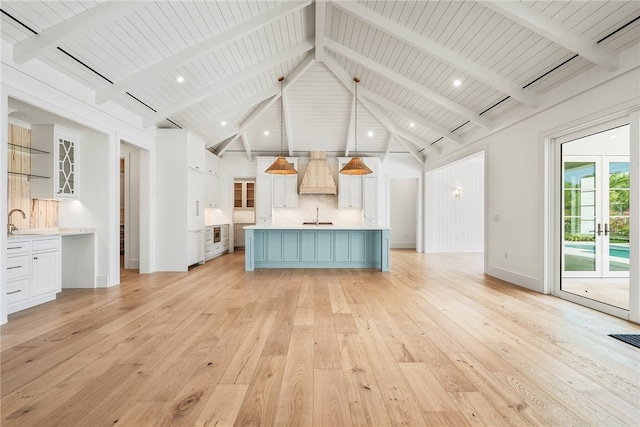 kitchen with white cabinetry, custom exhaust hood, pendant lighting, light hardwood / wood-style flooring, and sink