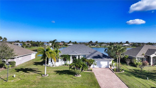 view of front facade featuring a water view, a garage, and a front lawn