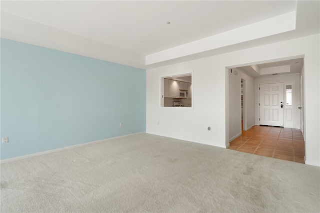 unfurnished room featuring light carpet and a raised ceiling