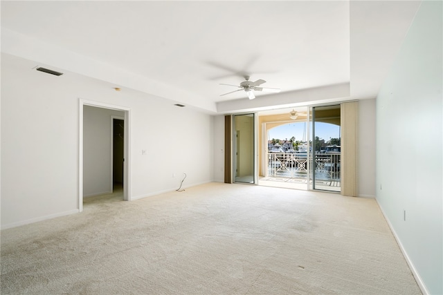 carpeted empty room featuring ceiling fan and a water view