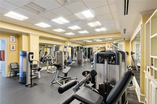 workout area with ornamental molding and a drop ceiling