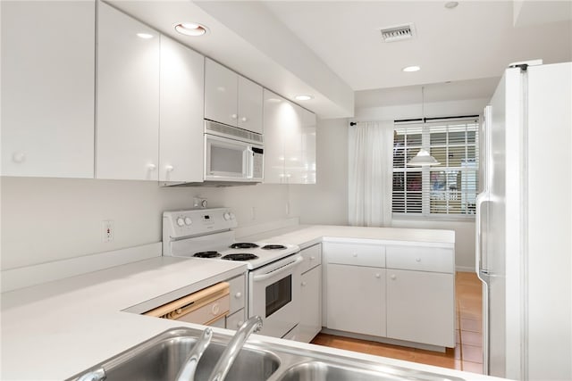 kitchen featuring white cabinetry, kitchen peninsula, hanging light fixtures, and white appliances