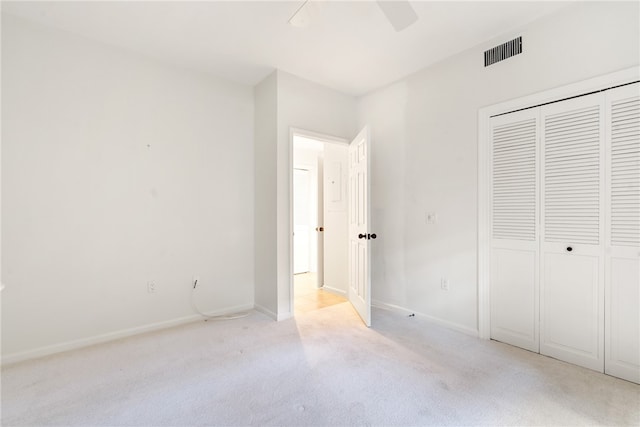 unfurnished bedroom featuring light colored carpet, ceiling fan, and a closet