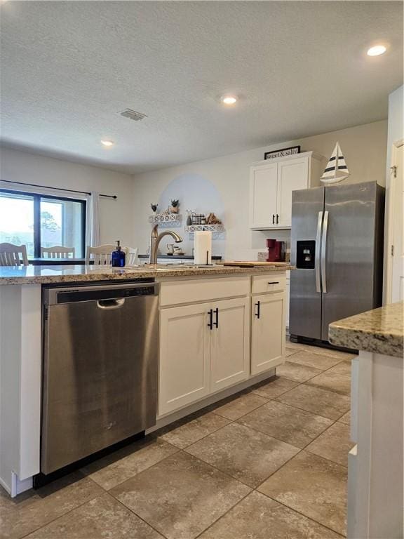 kitchen featuring white cabinetry, sink, stainless steel appliances, light stone countertops, and a textured ceiling