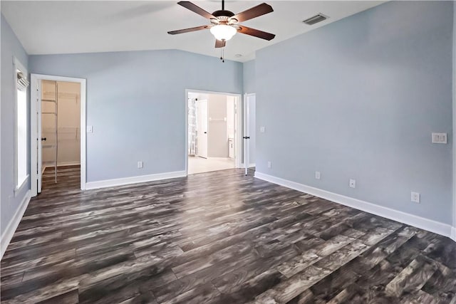 unfurnished bedroom with lofted ceiling, a walk in closet, ceiling fan, dark hardwood / wood-style floors, and a closet