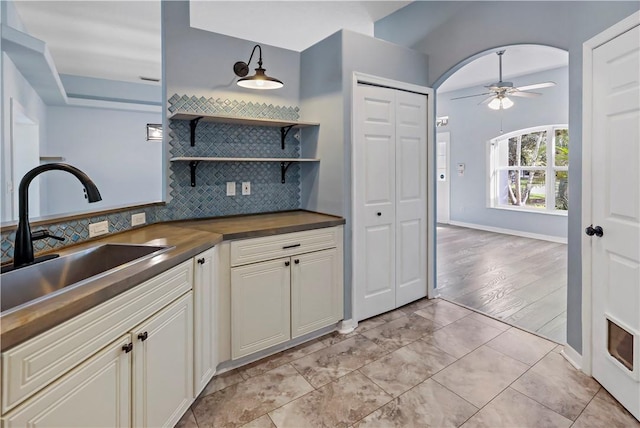 kitchen with butcher block counters, ceiling fan, sink, tasteful backsplash, and light tile patterned floors