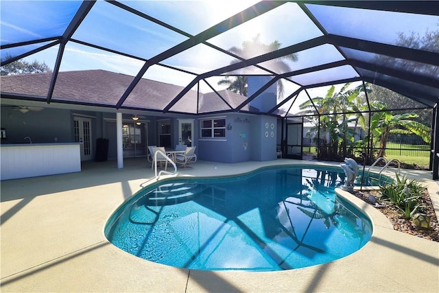 view of pool with exterior bar, a patio, and a lanai