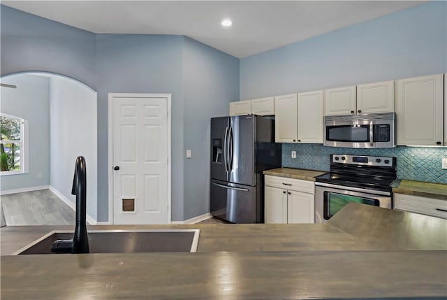 kitchen with sink, stainless steel appliances, backsplash, cream cabinets, and light hardwood / wood-style floors