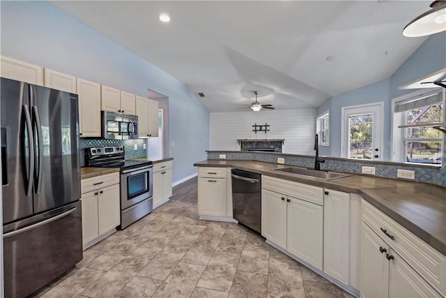 kitchen featuring ceiling fan, sink, stainless steel appliances, lofted ceiling, and decorative backsplash