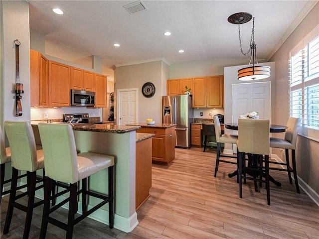 kitchen with stainless steel appliances, visible vents, light wood-style floors, a kitchen island, and a peninsula