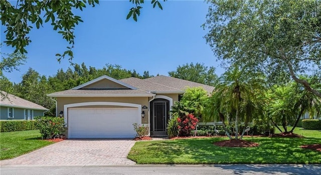 ranch-style house featuring a garage, decorative driveway, a front yard, and stucco siding