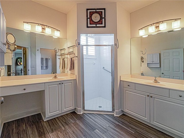 full bathroom featuring a stall shower, two vanities, a sink, and wood finished floors