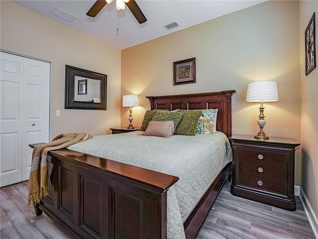 bedroom with light wood-type flooring, ceiling fan, visible vents, and a closet