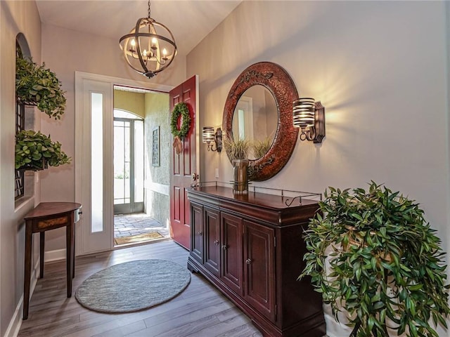 foyer with a chandelier, light wood-type flooring, and baseboards