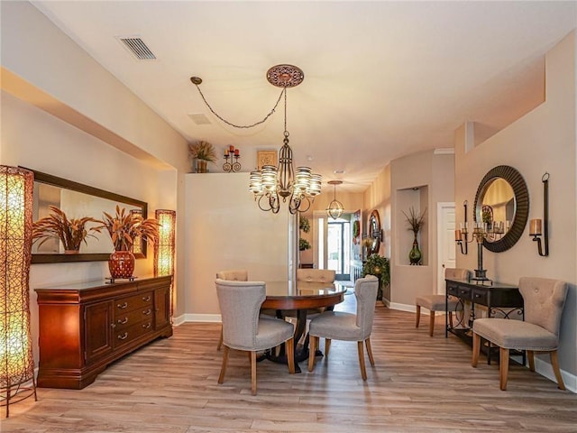 dining space with light wood-style floors, visible vents, a notable chandelier, and baseboards