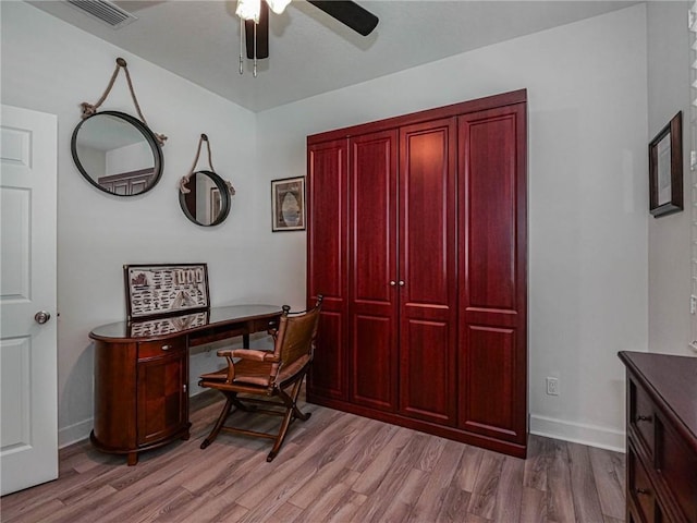 office space featuring a ceiling fan, visible vents, baseboards, and wood finished floors