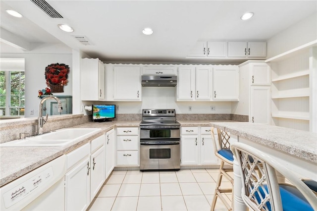 1300 Ivy Ct Unit 209, Vero Beach, FL 32963 - kitchen featuring range with two ovens, white dishwasher, a sink, under cabinet range hood, and light tile patterned floors