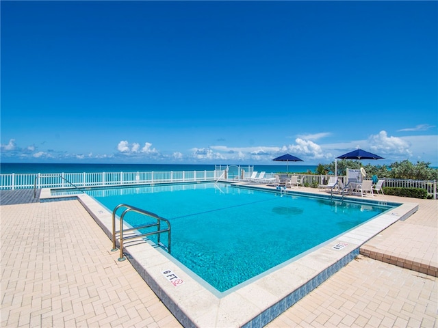 view of pool featuring a water view and a patio