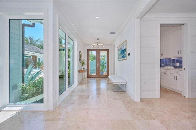 foyer entrance with crown molding, french doors, visible vents, and a chandelier