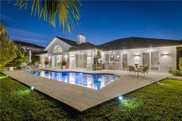 back of house featuring a patio, an exterior structure, an outdoor pool, a chimney, and an outdoor structure