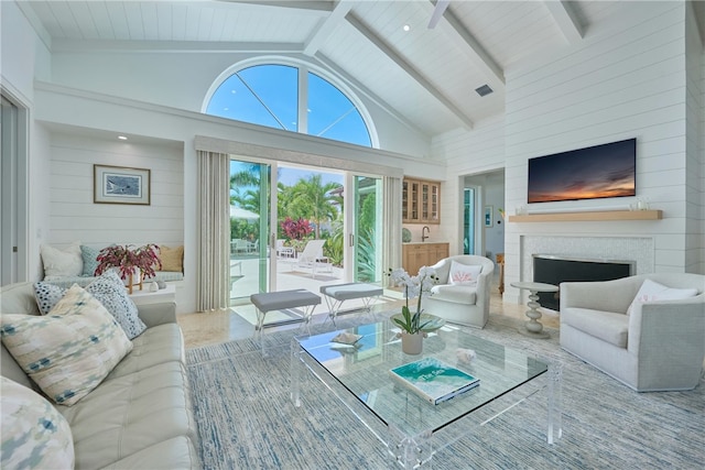 living room featuring beam ceiling, high vaulted ceiling, wood walls, and a fireplace